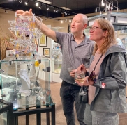 <p>BANDHU DUNHAM, glass artist, showing a guest how his marble run works!</p>